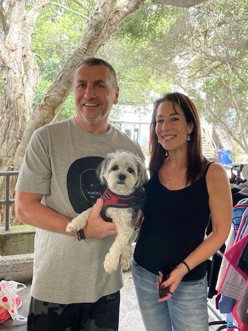 Image of Debbie and man with dog, in front of her fashion store